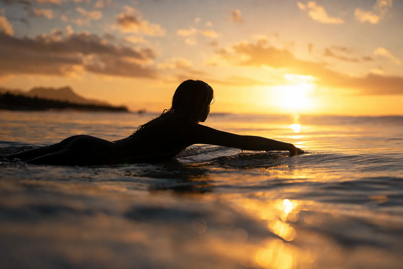 A lone surfer paddling out at golden hour, slow cinematic dolly shot, glassy waves, warm backlight, photorealistic