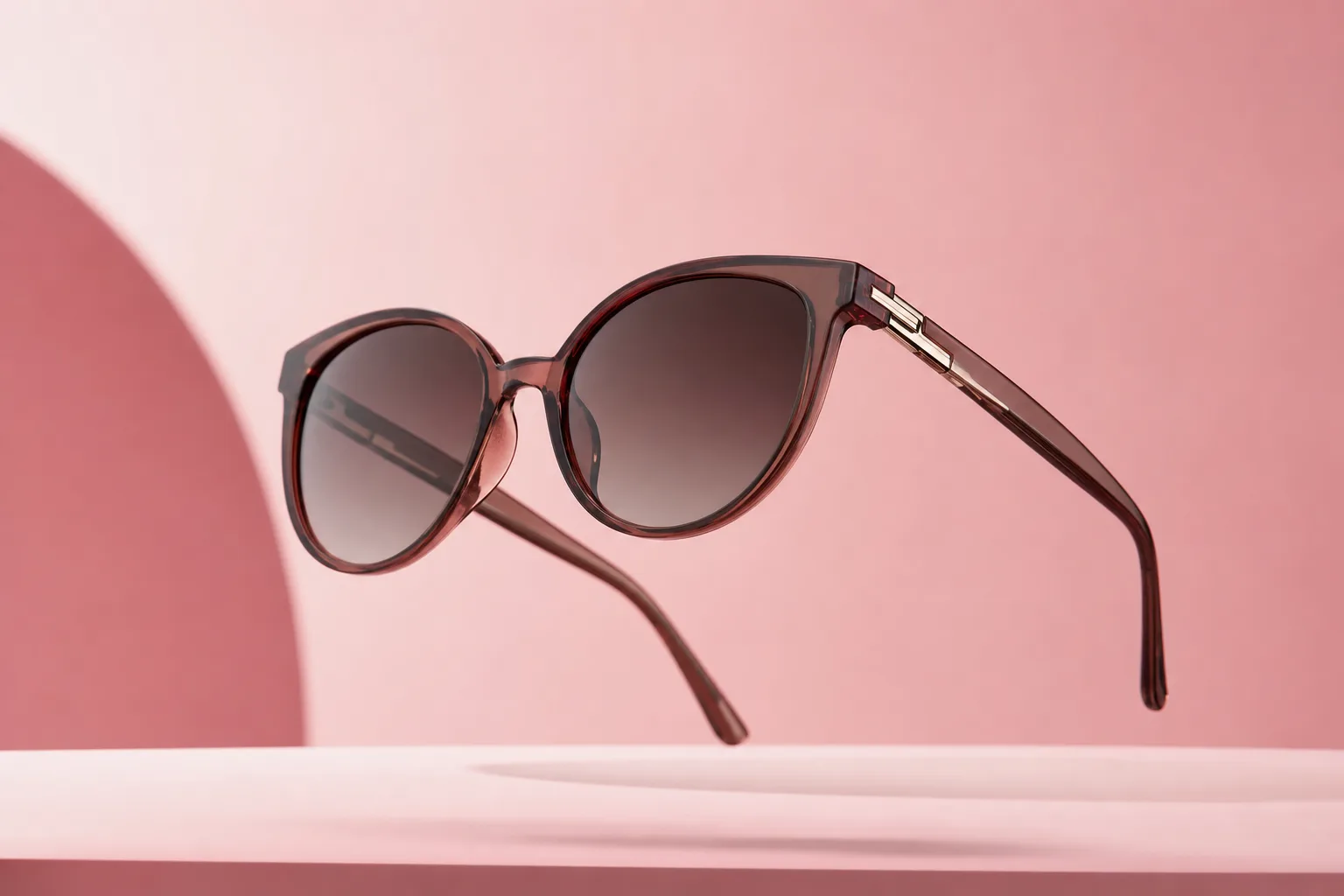 Designer sunglasses floating in a pastel pink minimalist studio.